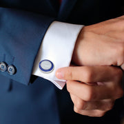 Man in navy suit adjusting his white French double cuff with a round silver cufflink